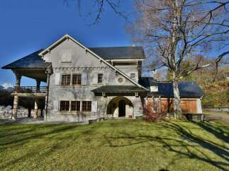 This stunning property boasts a unique architectural design with a stone facade and a charming balcony.