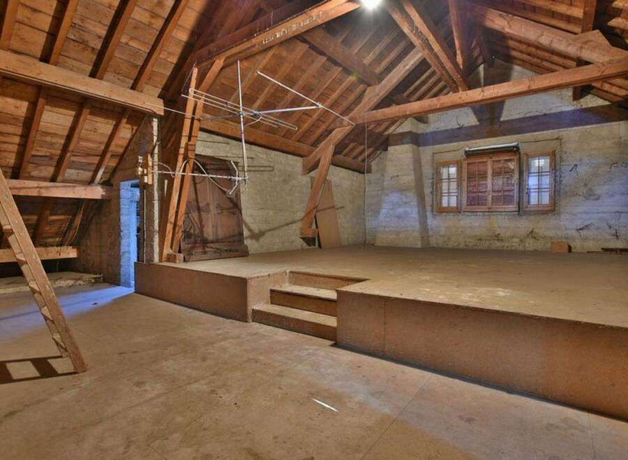Discover the charm of this unique property, featuring a spacious attic with exposed wooden beams.