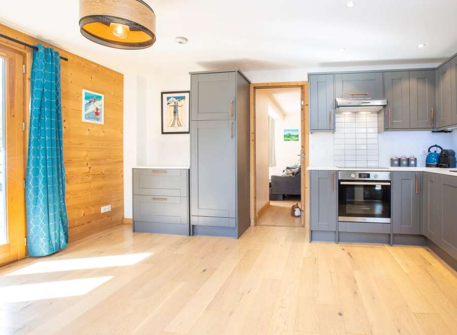 This stunning kitchen boasts modern gray cabinetry, complemented by sleek copper hardware and a stainless steel oven.