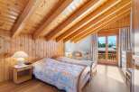 This charming bedroom features a cozy, wooden-paneled interior and a unique sloped ceiling with exposed beams, creating a warm and inviting atmosphere.
