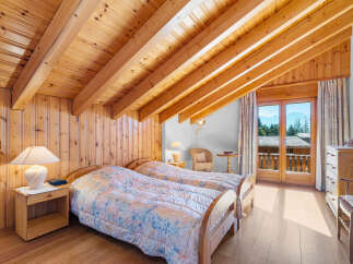 This charming bedroom features a cozy, wooden-paneled interior and a unique sloped ceiling with exposed beams, creating a warm and inviting atmosphere.