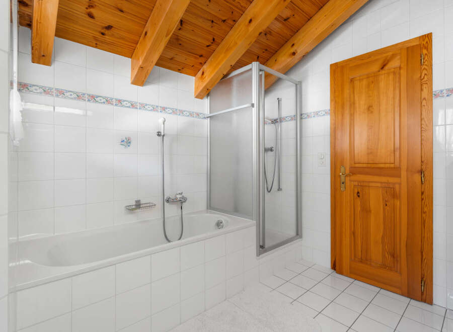 This charming bathroom features a classic design with a wooden ceiling and a bright, airy feel.