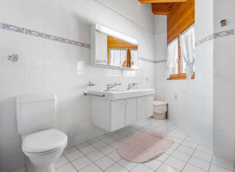 This bright and airy bathroom features a clean, modern design with white tile walls and flooring.