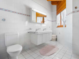 This bright and airy bathroom features a clean, modern design with white tile walls and flooring.