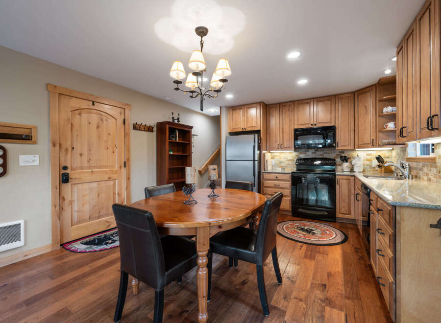 This charming kitchen features warm wood cabinetry, a stainless steel refrigerator, and a black oven and microwave.