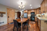 This charming kitchen features warm wood cabinetry, a stainless steel refrigerator, and a black oven and microwave.