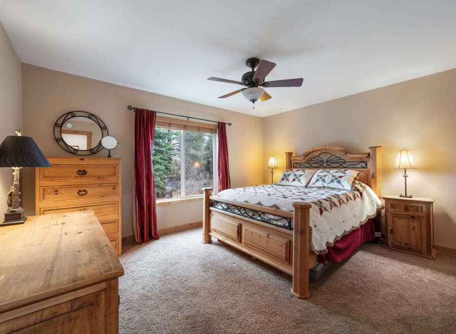 This cozy bedroom features a rustic wooden bed frame, complemented by matching nightstands and a dresser, creating a warm and inviting atmosphere.
