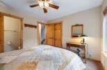 This cozy bedroom features a rustic design with wooden accents and a charming ceiling fan.