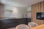 This modern kitchen boasts sleek, dark cabinetry and a stylish countertop, perfect for culinary enthusiasts.