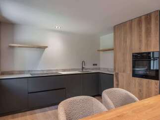 This modern kitchen boasts sleek, dark cabinetry and a stylish countertop, perfect for culinary enthusiasts.