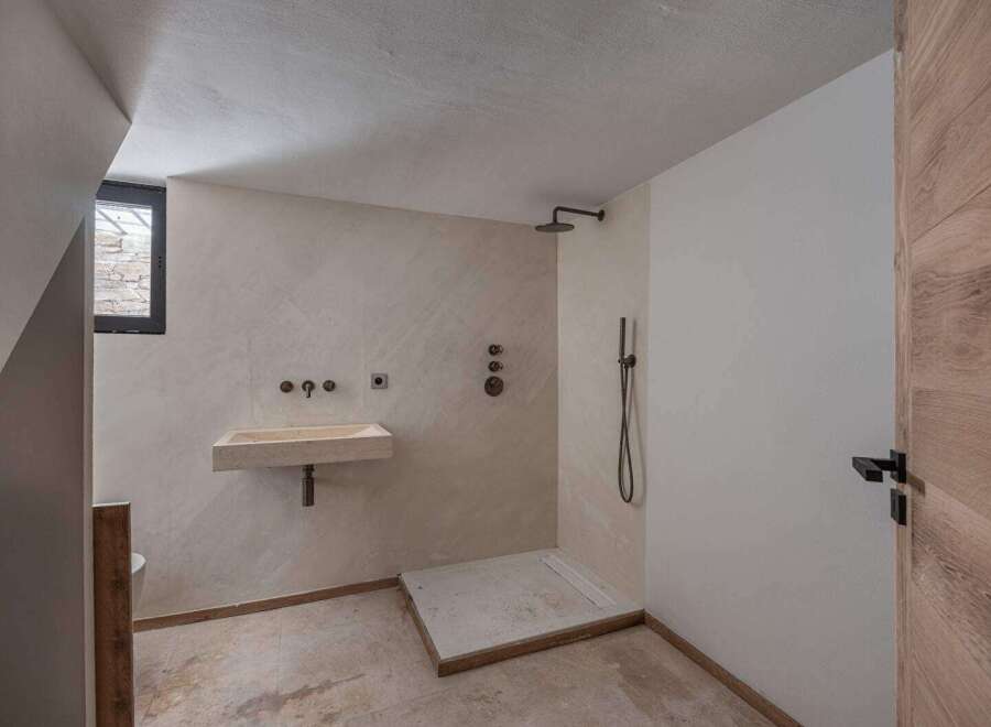 This modern bathroom features a sleek, minimalist design with a walk-in shower and a floating sink.