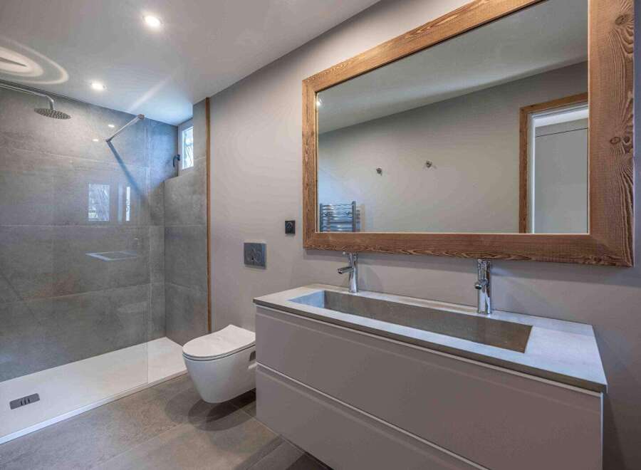 This modern bathroom features a sleek design with a spacious shower and a stylish vanity.