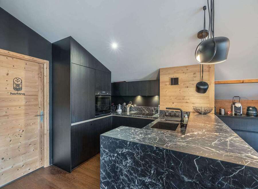 This modern kitchen boasts sleek black cabinetry and a stunning marble countertop, creating a sophisticated and stylish space.
