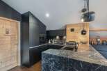 This modern kitchen boasts sleek black cabinetry and a stunning marble countertop, creating a sophisticated and stylish space.