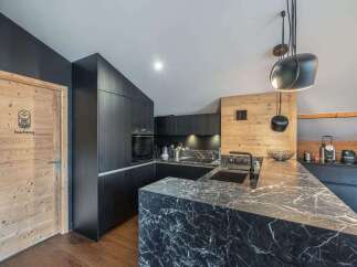 This modern kitchen boasts sleek black cabinetry and a stunning marble countertop, creating a sophisticated and stylish space.