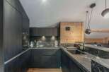This modern kitchen boasts sleek black cabinetry and stunning marble countertops, creating a sophisticated and stylish space.