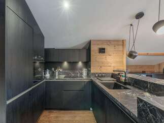 This modern kitchen boasts sleek black cabinetry and stunning marble countertops, creating a sophisticated and stylish space.