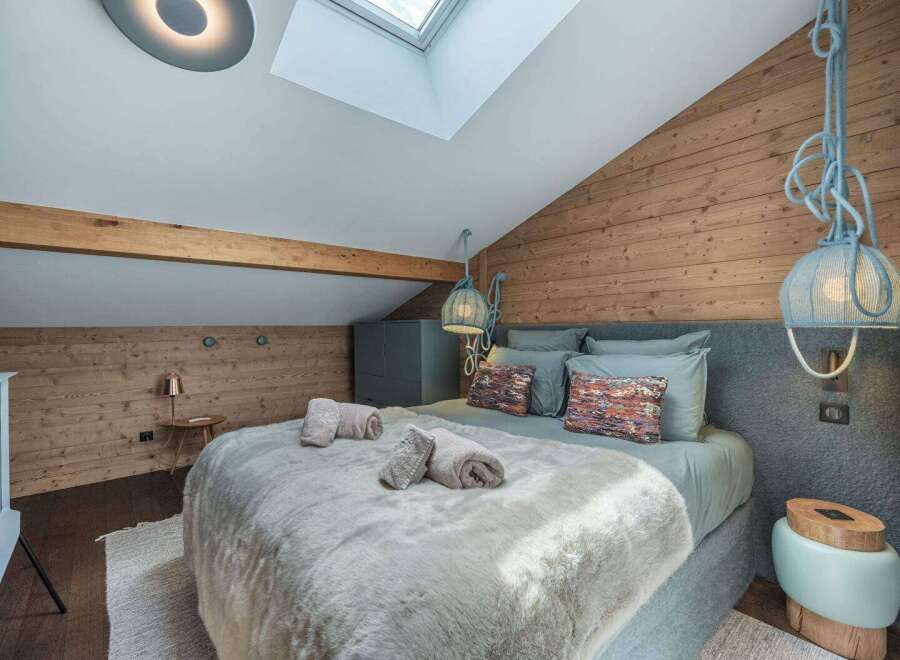 Discover the charm of this cozy bedroom, featuring a unique wooden wall and a stylish bed.
