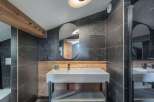 This modern bathroom features a sleek design with dark tiled walls and a wooden accent wall.