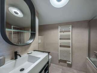 This modern bathroom features a sleek design with a large, oval mirror and a stylish sink.