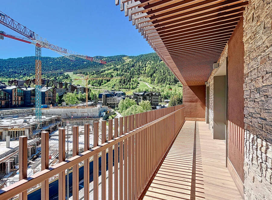 Experience breathtaking views from this stunning balcony overlooking a vibrant cityscape and lush mountains.