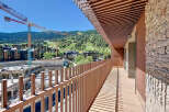 Experience breathtaking views from this stunning balcony overlooking a vibrant cityscape and lush mountains.