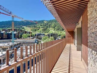 Experience breathtaking views from this stunning balcony overlooking a vibrant cityscape and lush mountains.
