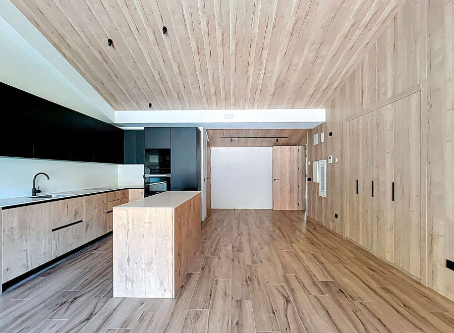 Discover modern elegance in this stunning property featuring a sleek kitchen with black cabinetry and a stylish island.