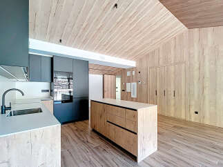 This modern kitchen boasts a sleek design with a wooden ceiling and walls, creating a warm and inviting atmosphere.