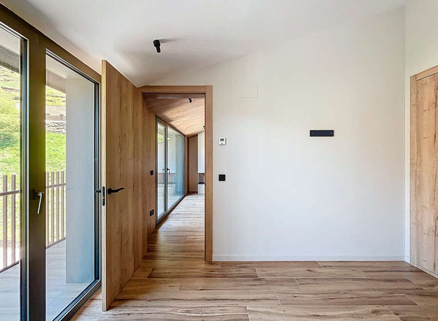 Discover modern elegance in this stunning property, featuring sleek wooden accents and expansive glass doors that flood the space with natural light.
