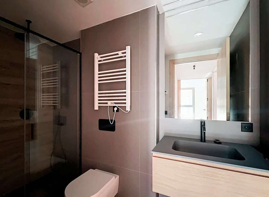 Step into a modern bathroom oasis! This stylish space features a sleek glass shower, a contemporary sink, and a heated towel rack.