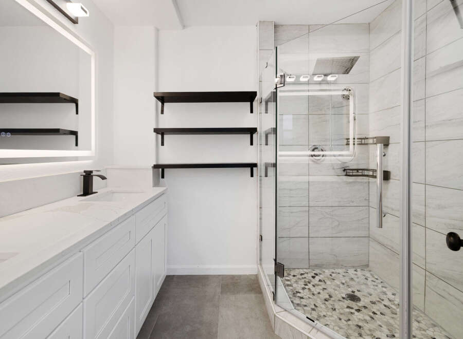 Step into luxury with this stunning bathroom! Featuring a sleek, modern design, this space boasts a pristine white vanity, elegant black fixtures, and ample storage.
