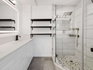 Step into luxury with this stunning bathroom! Featuring a sleek, modern design, this space boasts a pristine white vanity, elegant black fixtures, and ample storage.