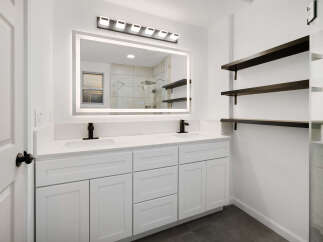 This stunning bathroom boasts a modern design with sleek white cabinetry and a pristine countertop.