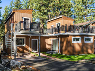 This stunning property features a modern design with a unique spiral staircase and multiple balconies, perfect for enjoying the surrounding natural beauty.