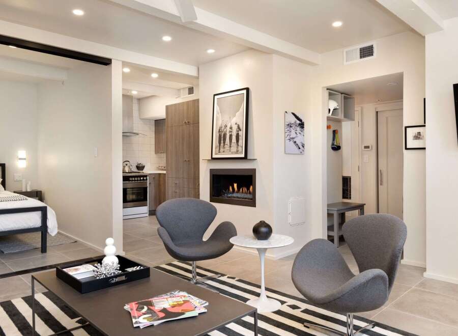 Experience modern living in this stylish property, featuring a cozy fireplace and chic gray armchairs.