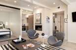 Experience modern living in this stylish property, featuring a cozy fireplace and chic gray armchairs.