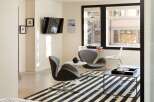 This modern living space features a sleek design with a mounted TV, stylish seating, and a striking black and white striped rug.
