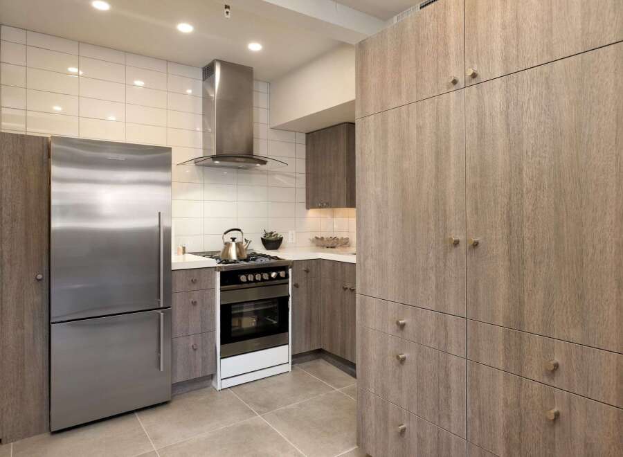 This modern kitchen boasts sleek, wood-paneled cabinetry and stainless steel appliances, creating a stylish and functional space.