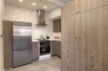 This modern kitchen boasts sleek, wood-paneled cabinetry and stainless steel appliances, creating a stylish and functional space.