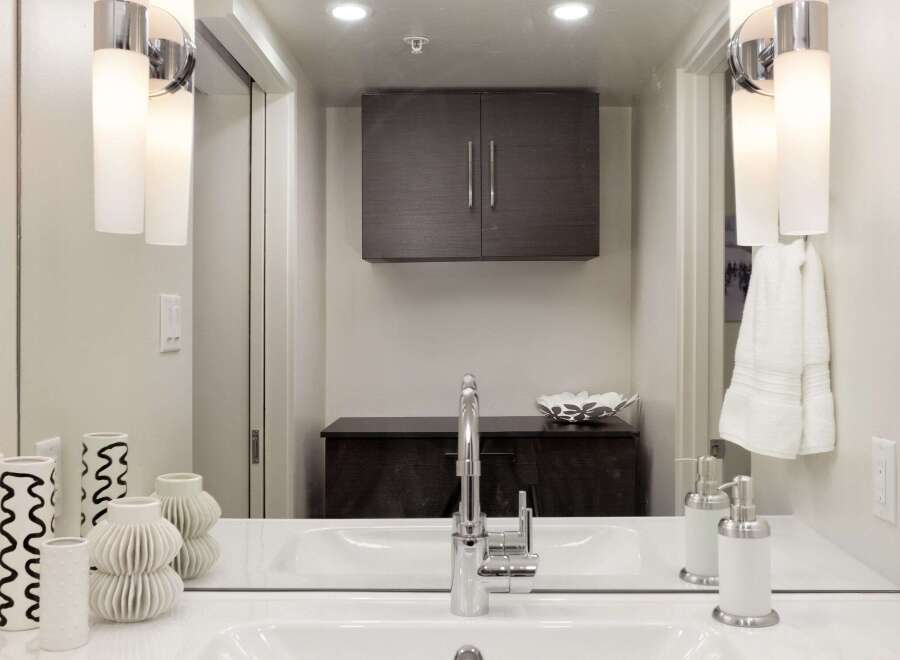This modern bathroom features a sleek design with a large mirror and stylish lighting fixtures.