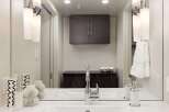 This modern bathroom features a sleek design with a large mirror and stylish lighting fixtures.