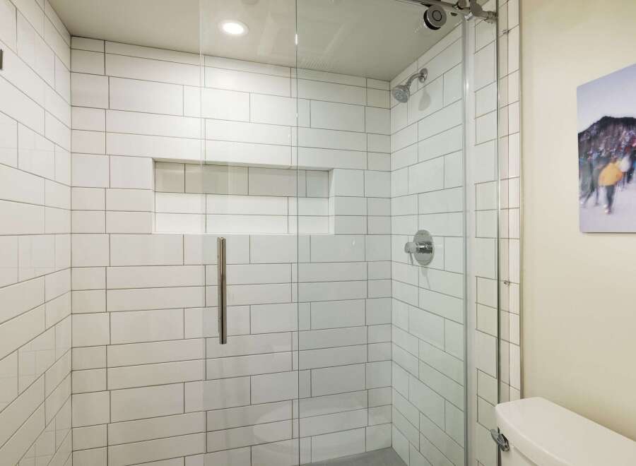 Step into a modern bathroom oasis! This space features a sleek, glass-enclosed shower with pristine white subway tile, offering a clean and contemporary aesthetic.