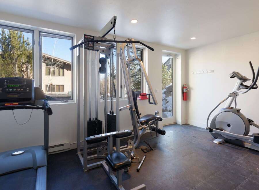 This home gym offers a comprehensive workout space with a treadmill, elliptical machine, and a multi-station weight machine.