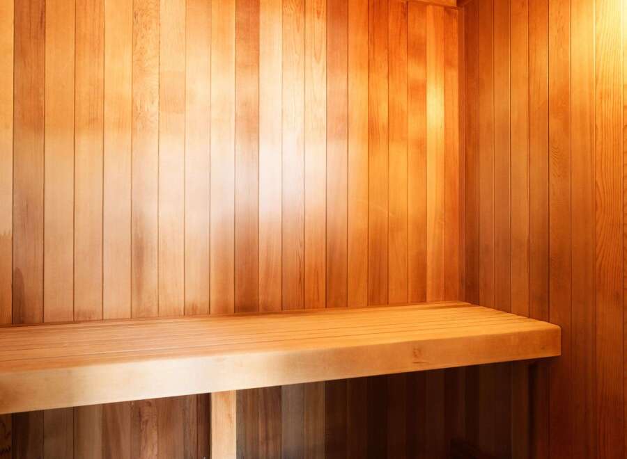 Step into relaxation with this stunning sauna, featuring beautiful wooden paneling and a comfortable bench.