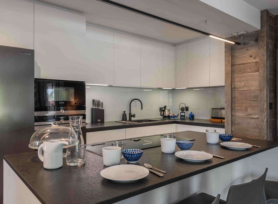 This modern kitchen boasts sleek white cabinetry and a dark countertop, creating a stylish and functional space.