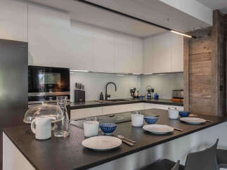 This modern kitchen boasts sleek white cabinetry and a dark countertop, creating a stylish and functional space.
