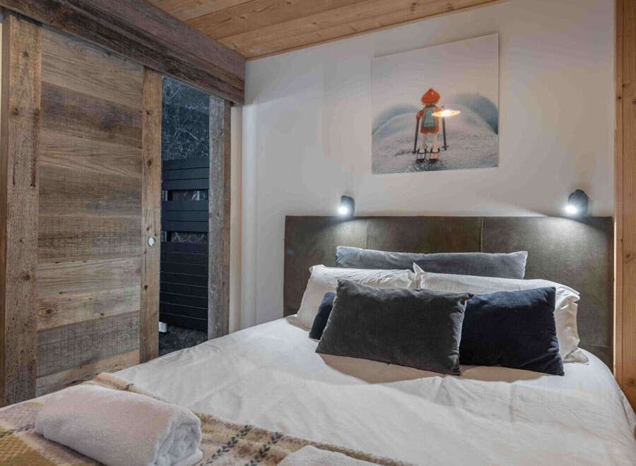 This cozy bedroom features a rustic wooden sliding door and a comfortable bed with plush pillows.