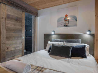 This cozy bedroom features a rustic wooden sliding door and a comfortable bed with plush pillows.
