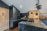 This modern kitchen boasts sleek black cabinetry and a stunning marble countertop, creating a sophisticated and stylish space.